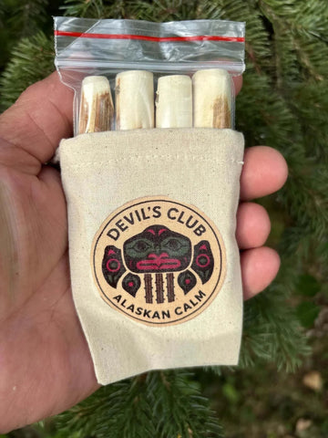 Alaskan Devil's Club Sticks are four light, hand-cut wood pieces in a beige canvas bag with a circular tribal design patch.
